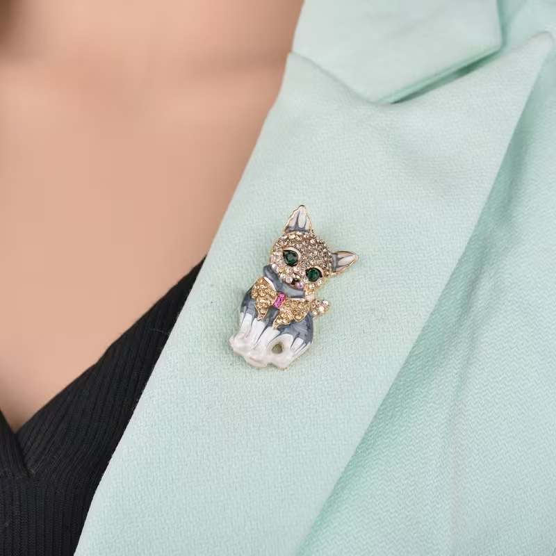 The cute and unique green-eyed cat brooch with alloy inlaid water diamonds and oil drops is a versatile clothing accessory